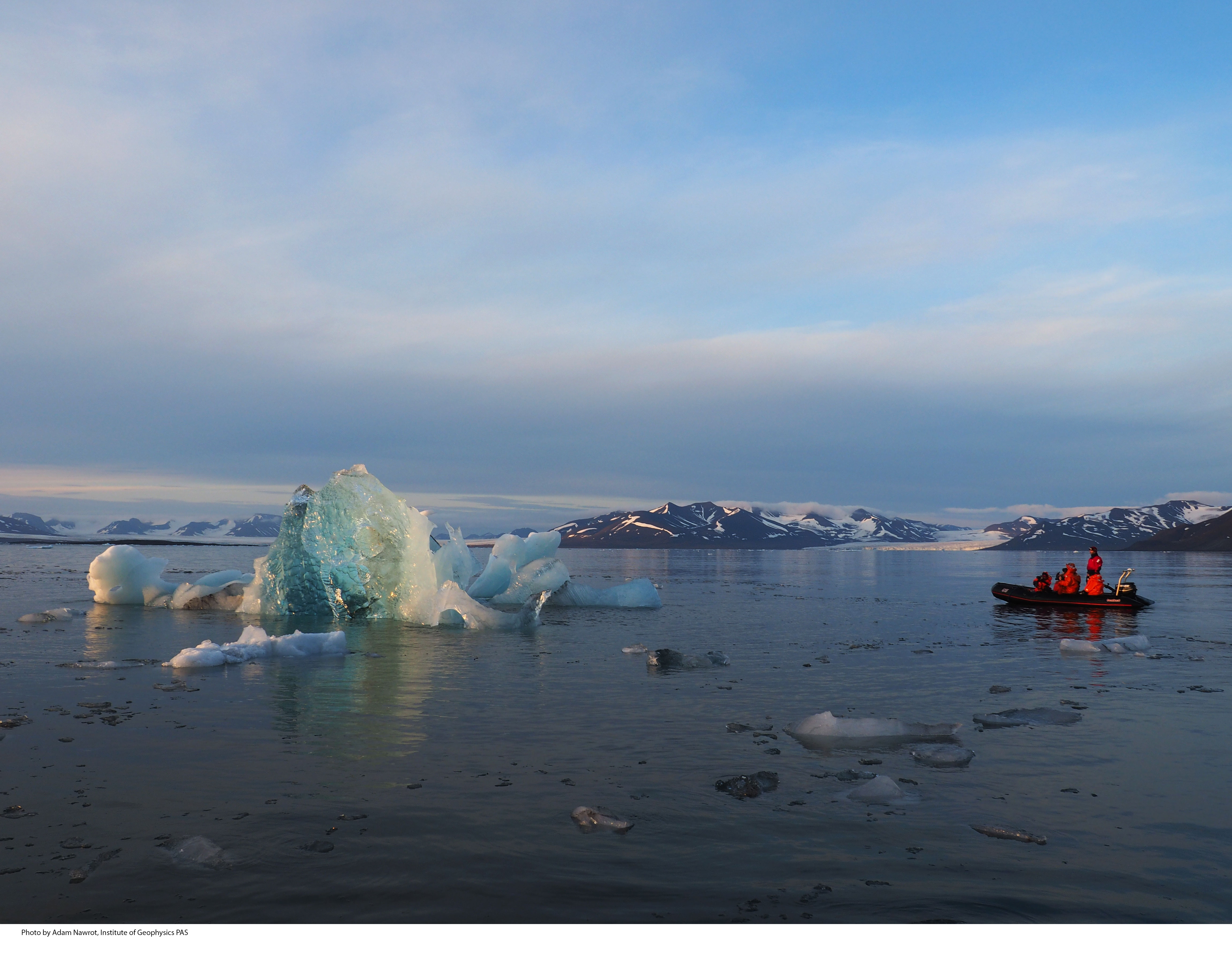 Researchers in dingy boat and a large iceberg in Svalbard